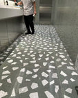 The white marble terrazzo on the floor of the mall's public restroom has a light green background